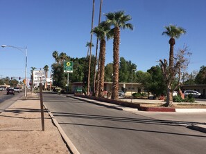 A street view with a Desert Inn sign, palm trees, and a building with an entrance.