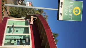 A Desert Inn hotel with a visible office sign, a clear view of the interior through the windows, and a sign indicating the availability of Wi-Fi and HBO services. - Desert Inn (Brawley)