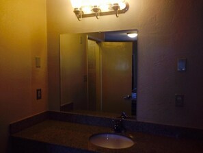 A bathroom with a sink, mirror, and light fixture.