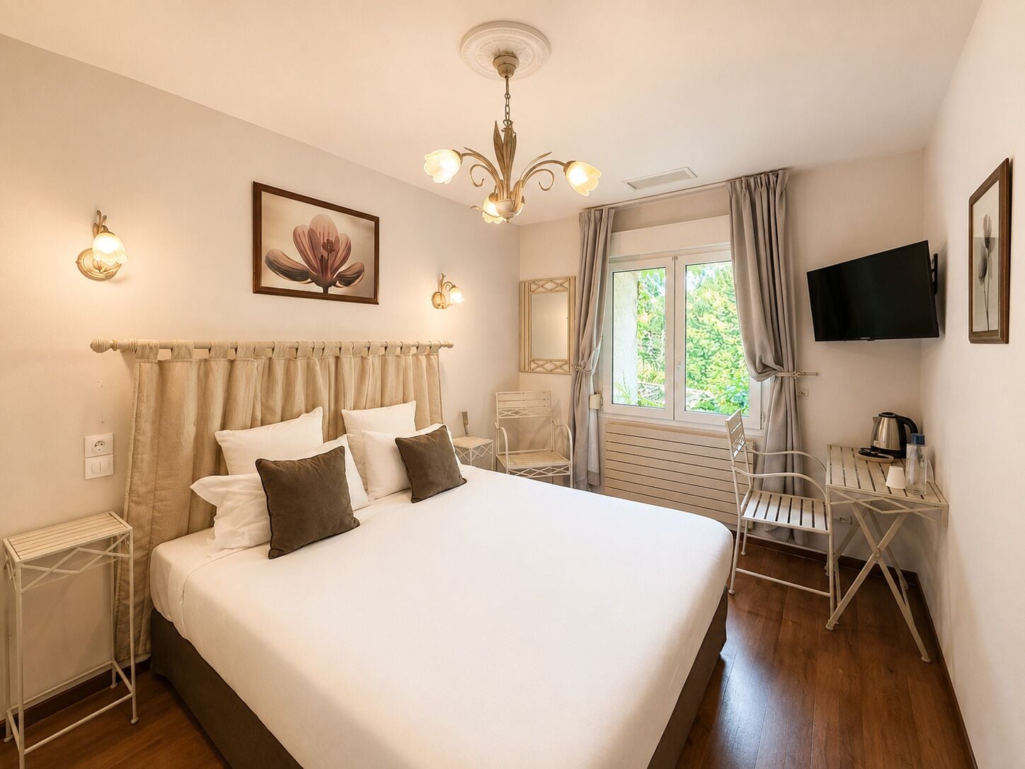 Una habitación de hotel con una cama grande, televisión, escritorio con silla y ventana con cortinas.