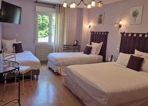 A hotel room with two beds, a table, a chair, a TV, and a window with curtains. -  Logis Hôtel restaurant Les Norias (Cazilhac)