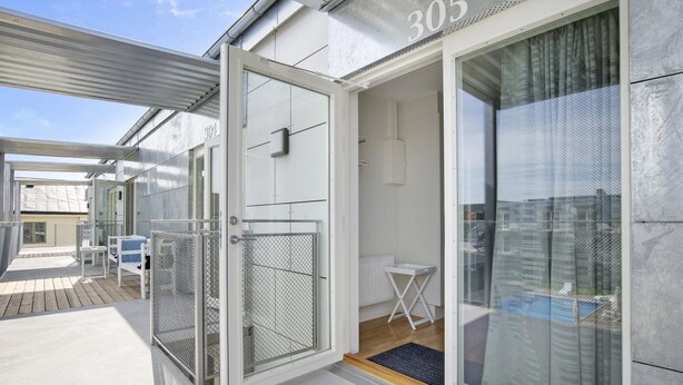 Una habitación de hotel moderna con puerta corredera de vidrio, una mesita y una silla.