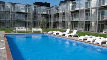 En sÀsongsöppen utomhuspool och solstolar