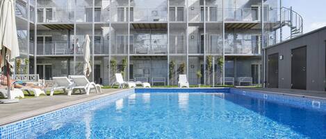 Een seizoensgebonden buitenzwembad, ligstoelen bij het zwembad