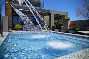 A swimming pool with a water feature, surrounded by lounge chairs and potted plants. - Wolken Lodge (Hengchun)