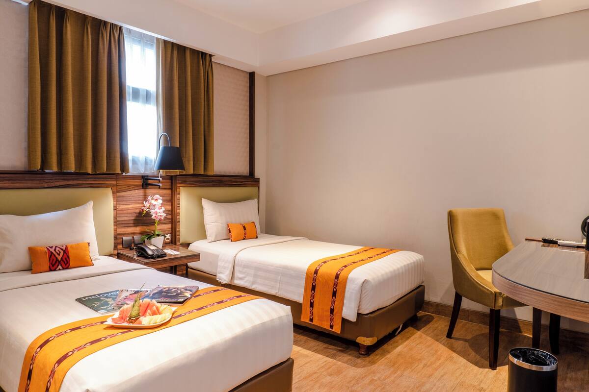 Habitación de hotel con dos camas, una mesa de comedor y un cubo de basura.