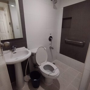 A bathroom with a toilet, sink, and shower area.