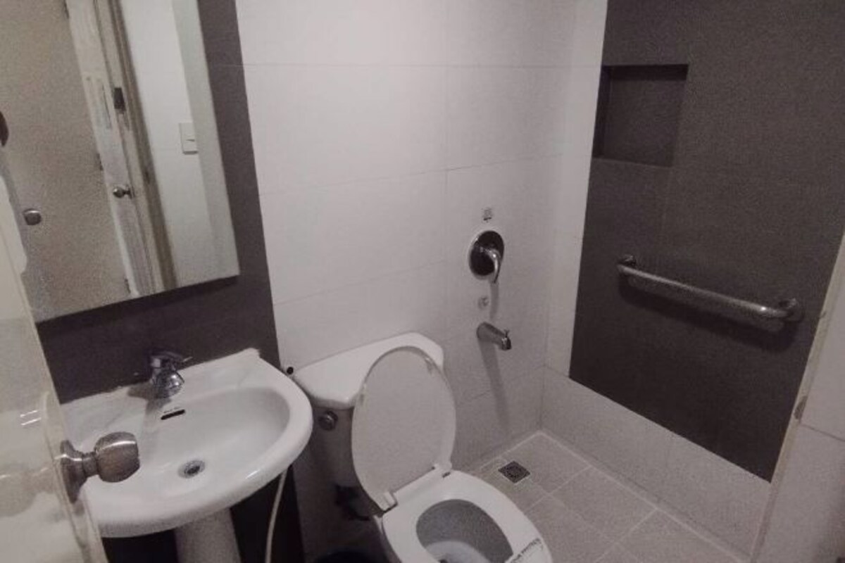 A small bathroom with a white sink, toilet, and a shower area.