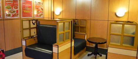 A restaurant with wooden panel walls, cushioned seating, and posters advertising food and beverage specials.