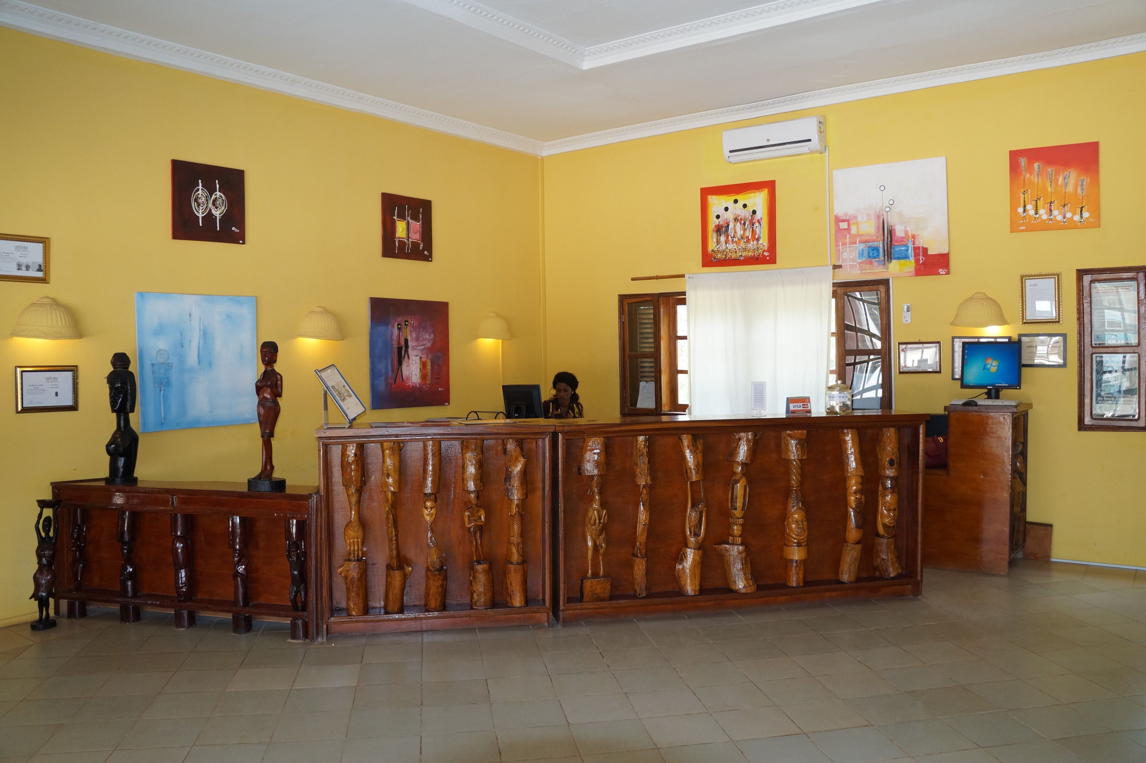 A reception area with a wooden reception desk, framed artwork on the walls, and a tiled floor.