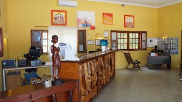 A reception area with a wooden reception desk, a statue, and framed artwork on the wall.