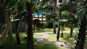 Ein üppiger Garten mit einem gewundenen Weg, Palmen und einem Poolbereich.