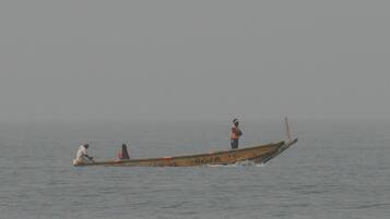 Un bote tradicional con tres personas navegando sobre aguas tranquilas.