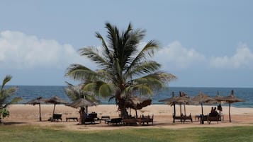 En la playa, sillas reclinables de playa, sombrillas, vóleibol de playa