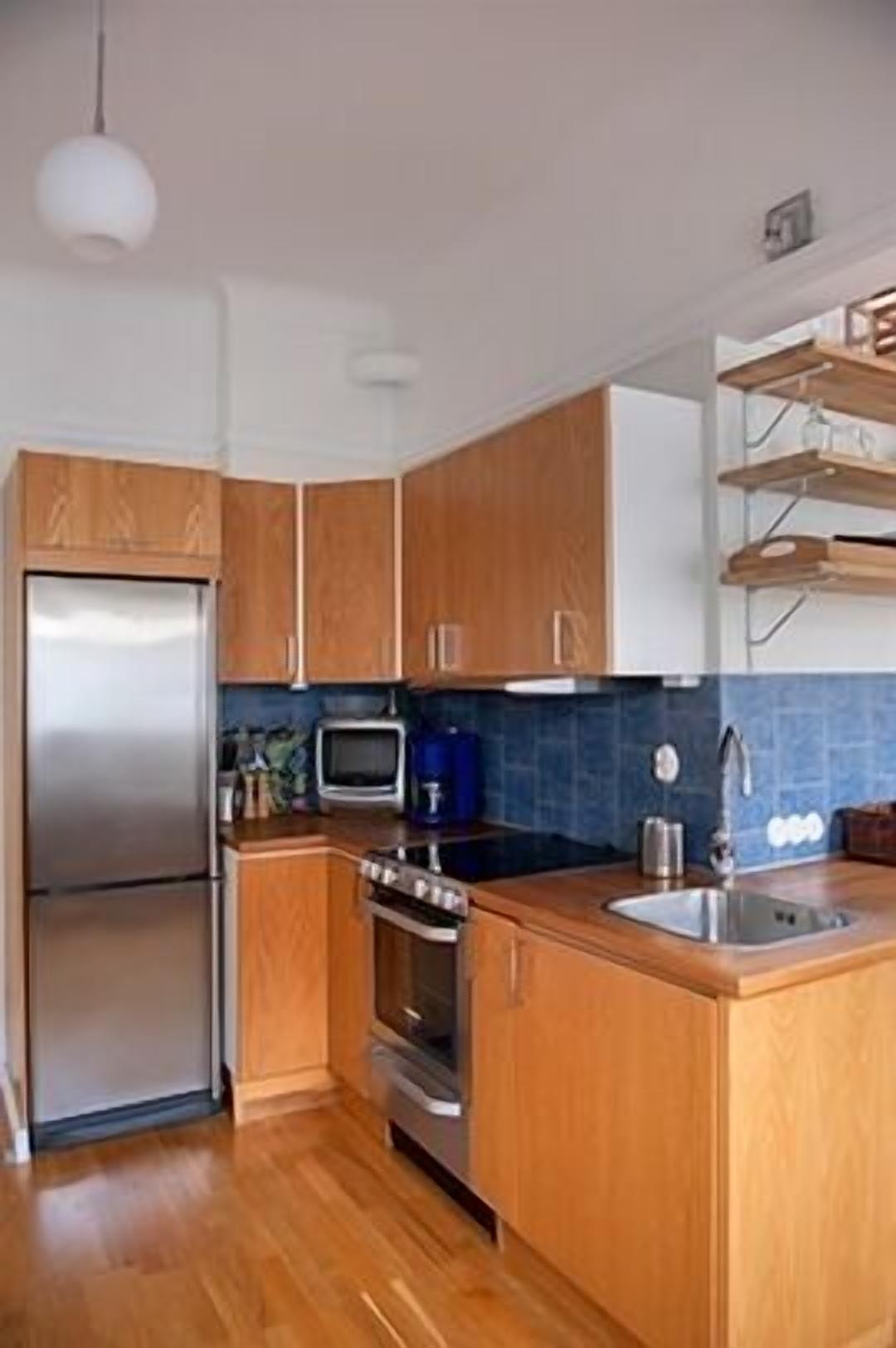 A kitchen with wooden cabinets, a stainless steel refrigerator, a microwave, and a sink.