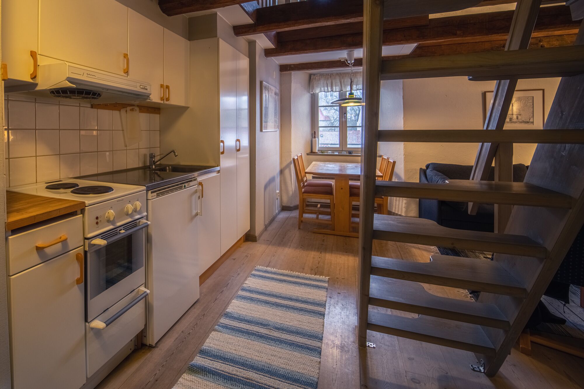 A kitchen with white cabinets, a stove, and a dining area with wooden chairs and a table.