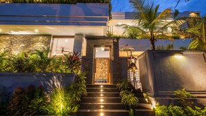 Una casa moderna con fachada de piedra, una puerta de madera y una escalera que conduce a la entrada.