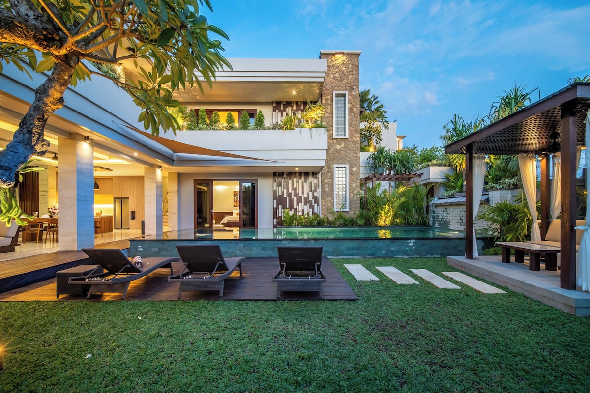 A modern house with a pool, outdoor seating, and a well-maintained garden.