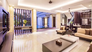 Un moderno vestíbulo de hotel con distribución amplia, una zona de piscina y una escalera que conduce a los pisos superiores.