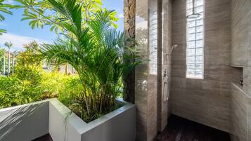 Une salle de bain moderne dotée d’une grande fenêtre, d’une douche et d’un bac à plantes contenant des plantes tropicales.