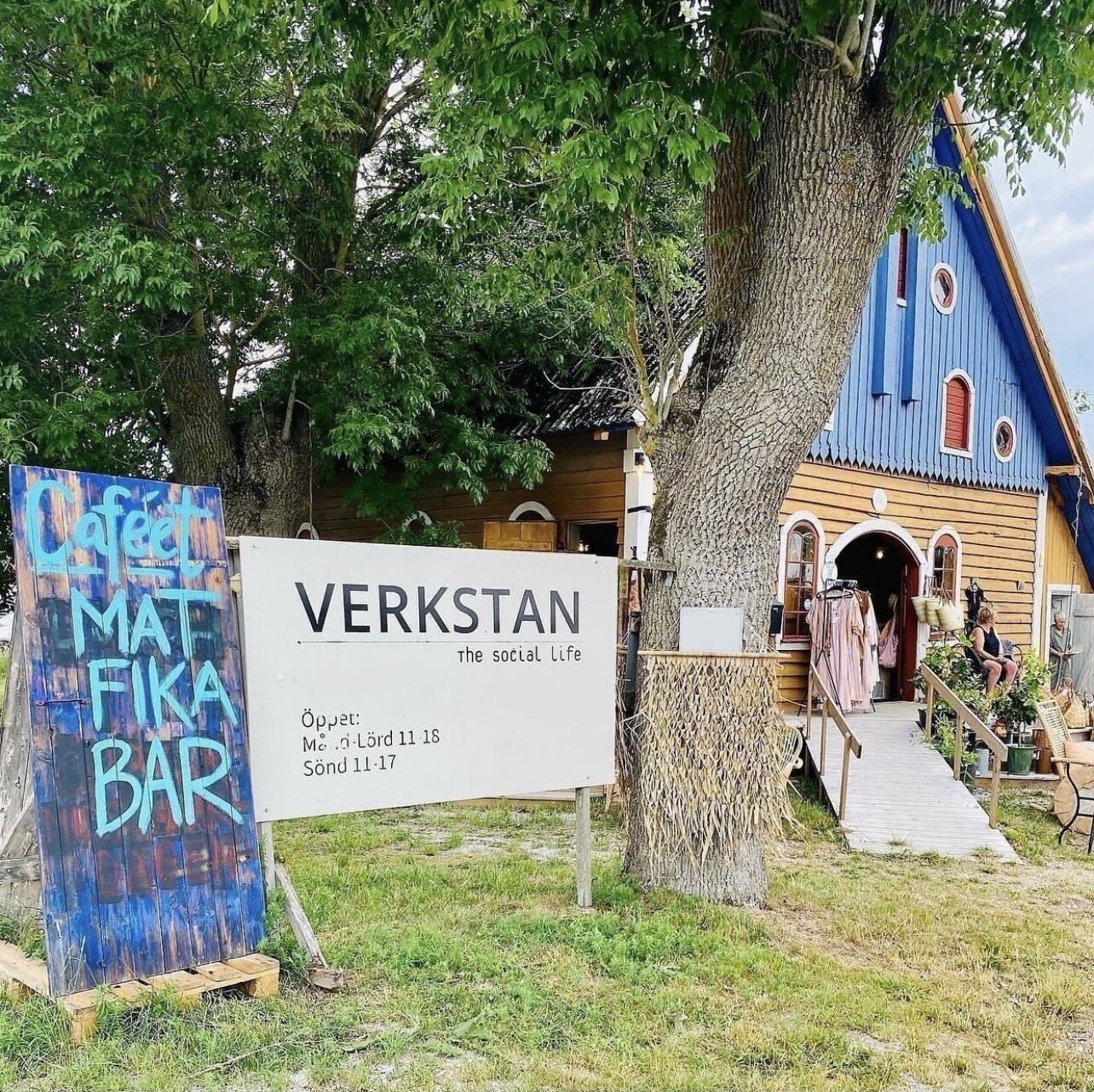 A sign for 'VERKSTAN - The social life' with operating hours and a nearby 'Café MAT FIKA BAR'.