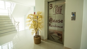 An elevator with a sign reading "3 @ease Residence" and a potted plant beside it. - At Ease Hotel Suvarnabhumi (Bang Phli)