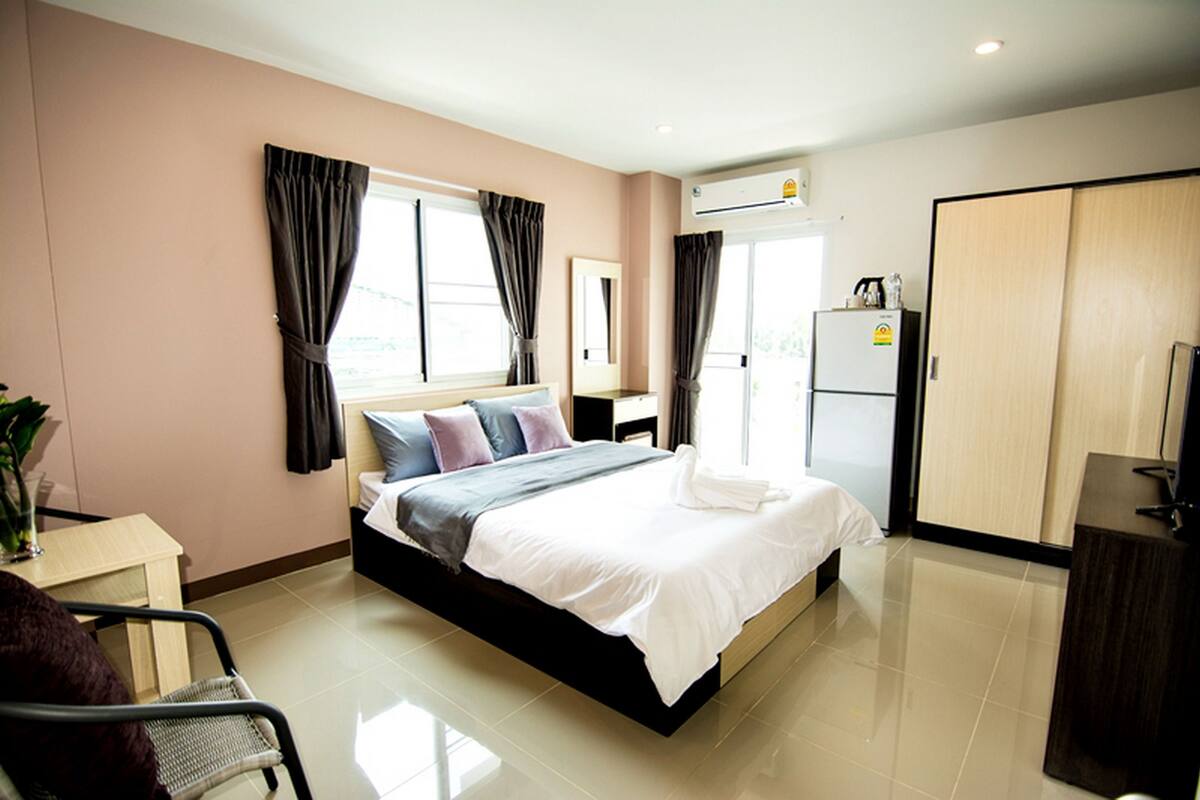 Une chambre d’hôtel équipée d’un lit, d’un bureau, d’une chaise, d’une armoire et d’un appareil de climatisation.