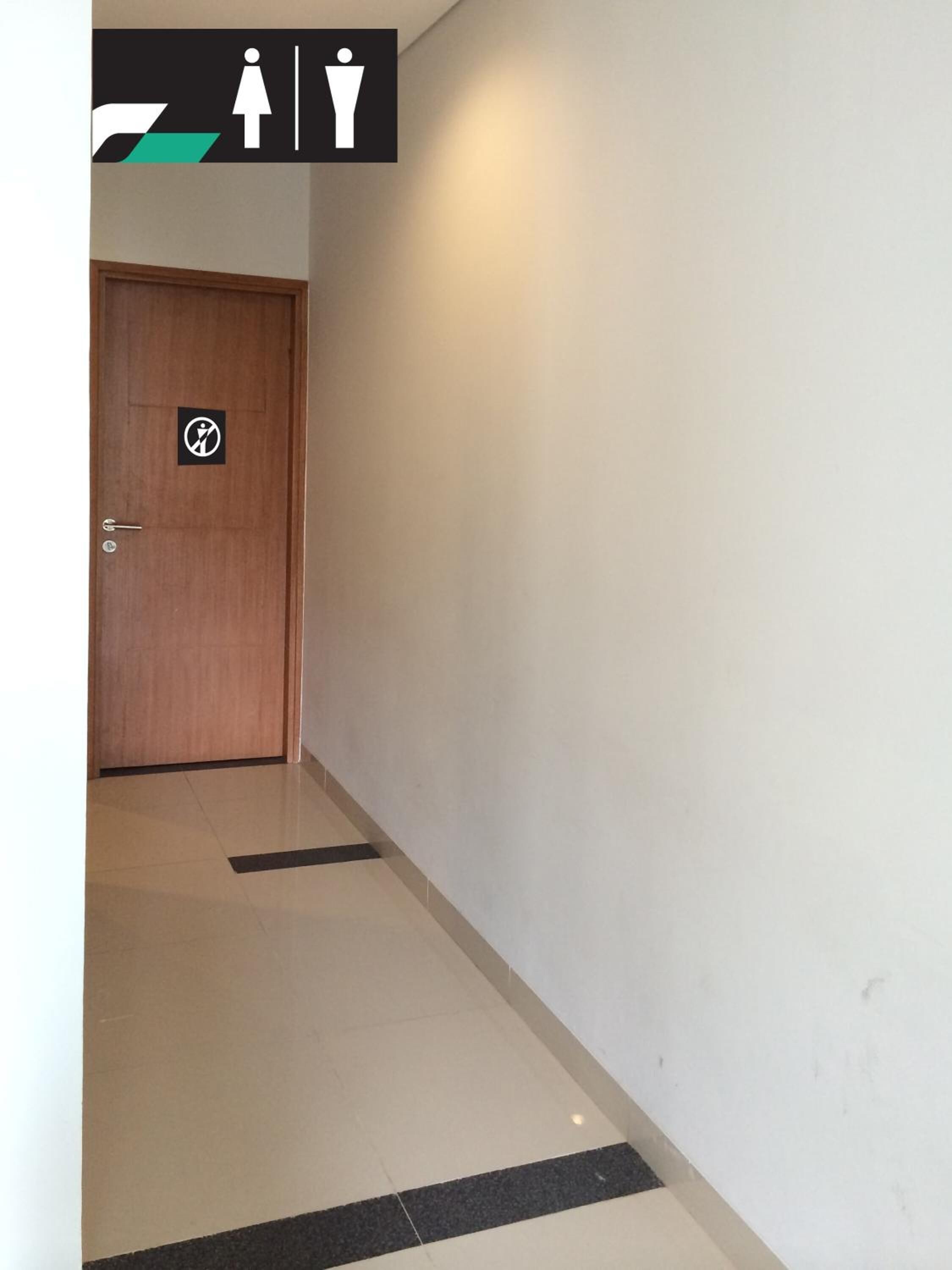 Pasillo con una puerta de madera señalizada con el símbolo de accesibilidad para sillas de ruedas.
