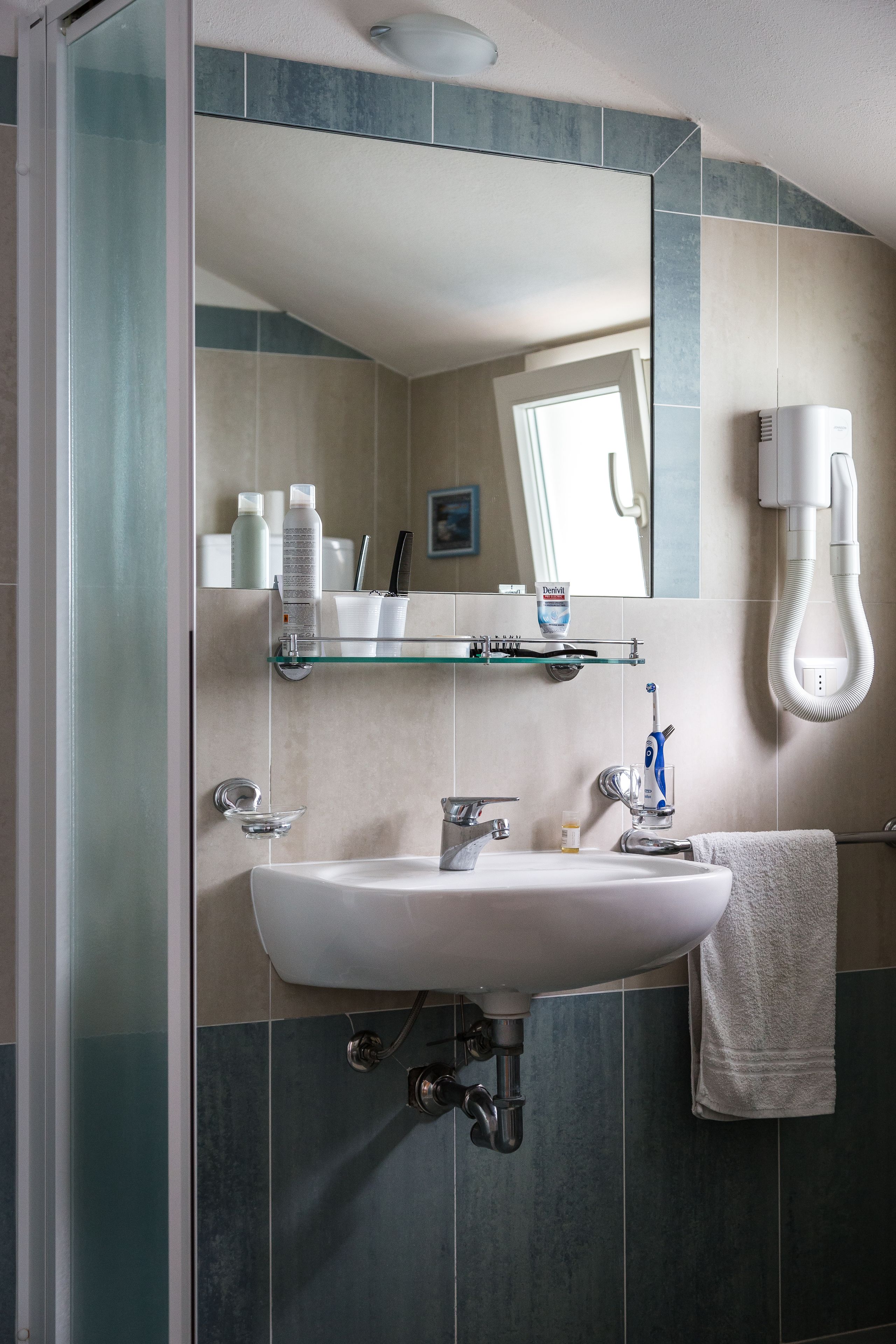 A bathroom with a glass shower enclosure, a white sink, a towel rack, and a mirror.
