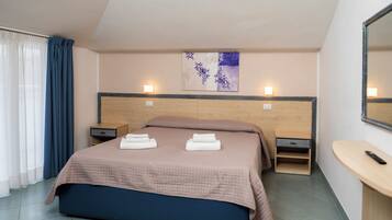 A neatly made bed with a headboard, bedside tables, a wall-mounted artwork, and a small wooden stool.