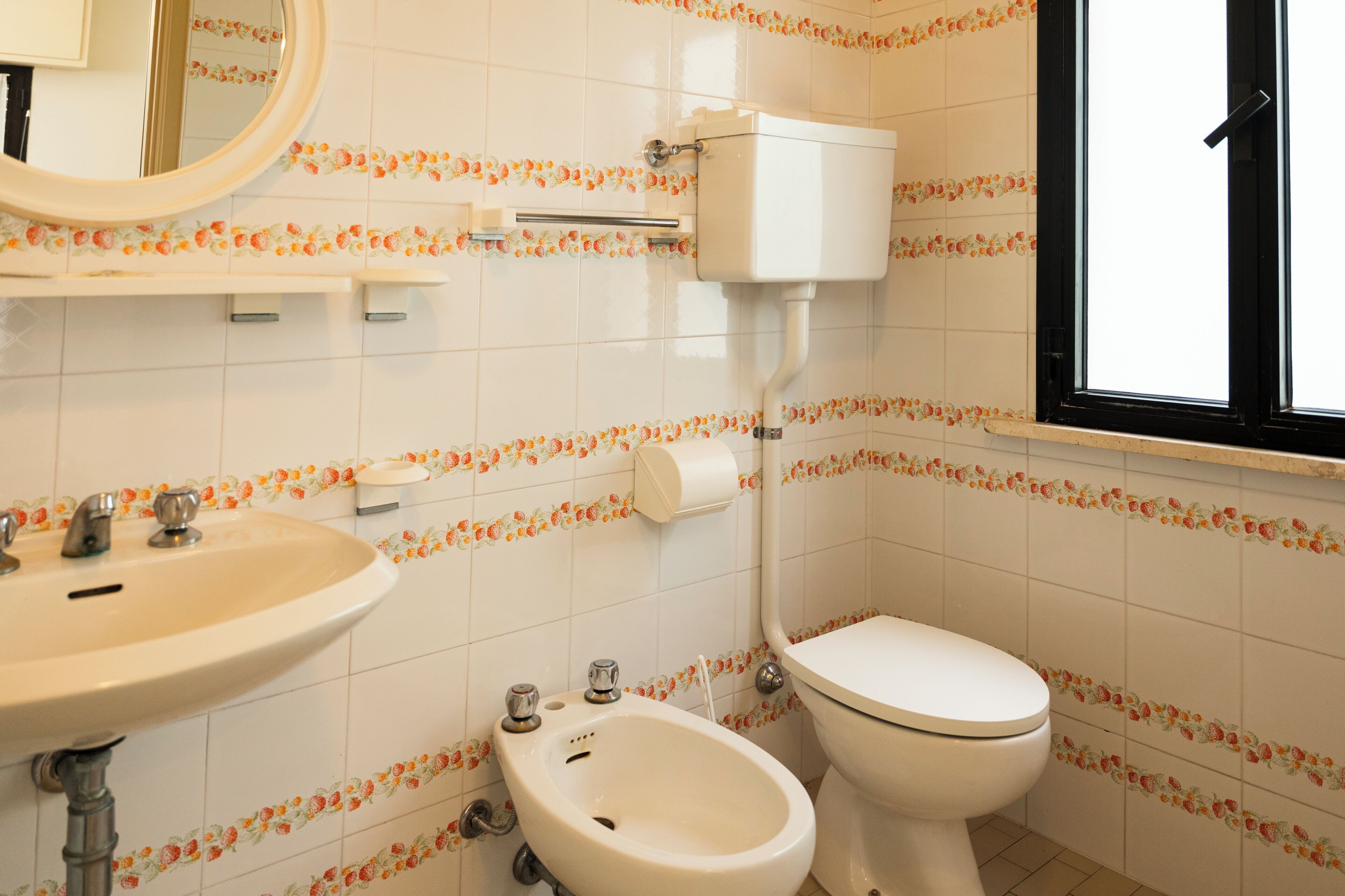 Une salle de bain équipée de toilettes, d’un bidet, d’un lavabo et d’un miroir.