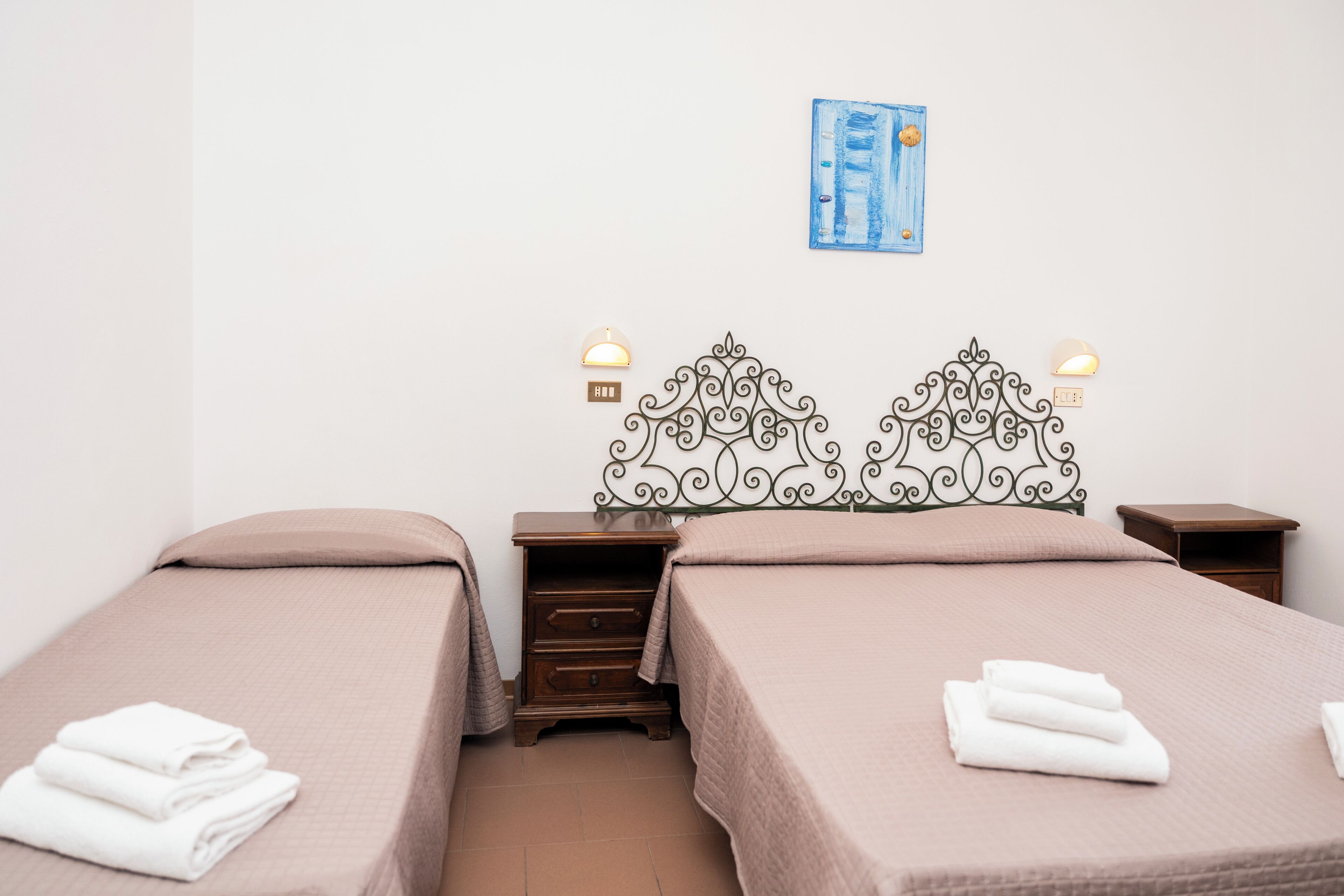 A double bed with a decorative headboard, a small bedside table, and a wall-mounted light fixture.