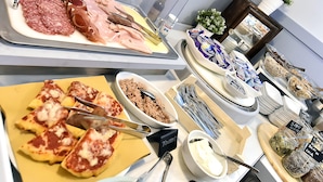 Een buffet met verschillende gerechten, waaronder vleeswaren, kazen en desserts.
