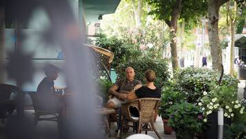 An outdoor seating area with wicker chairs, potted plants, and a shaded table.