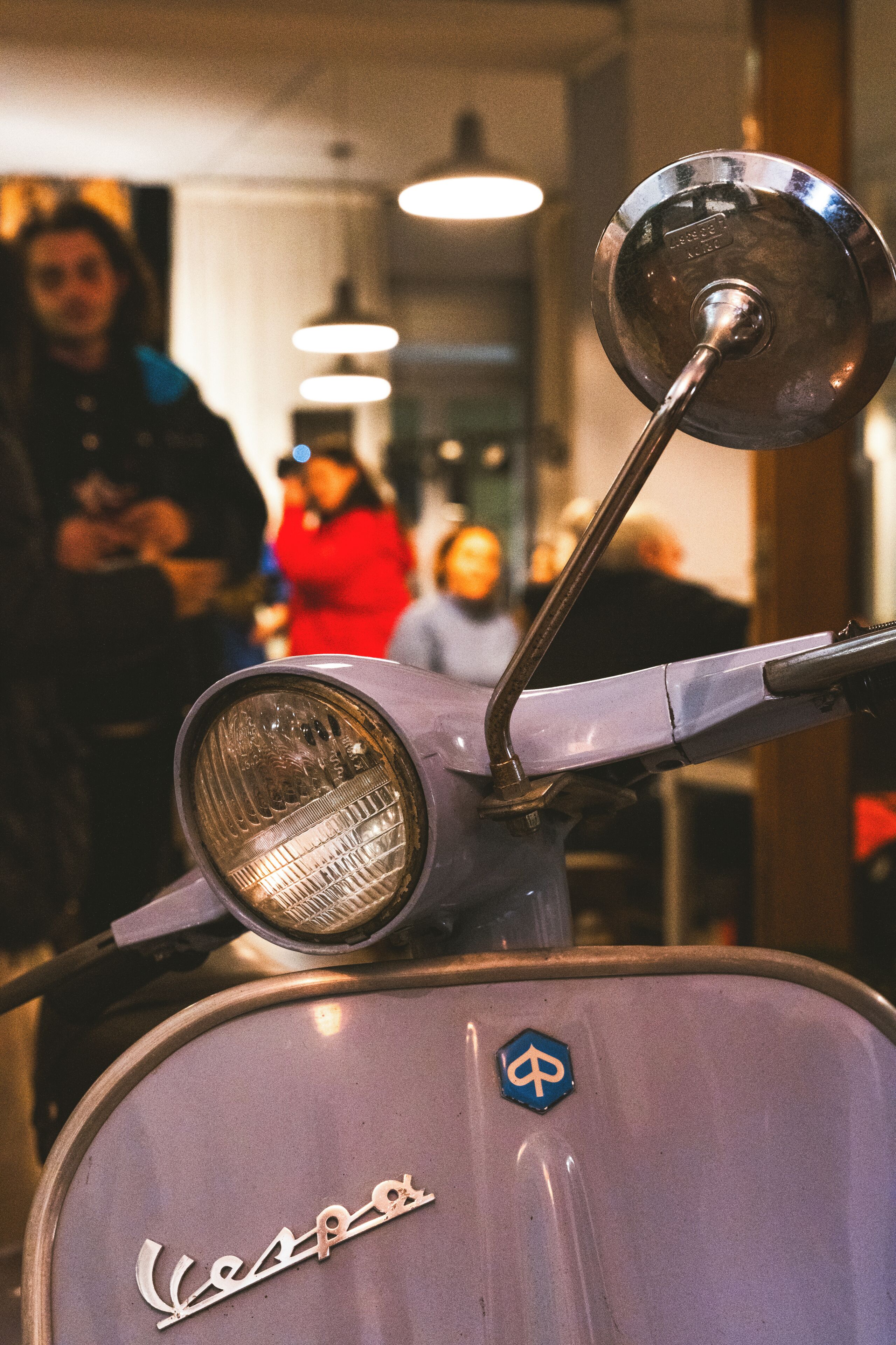 Un primo piano di un classico scooter Vespa, con il logo ben visibile e uno specchietto retrovisore.