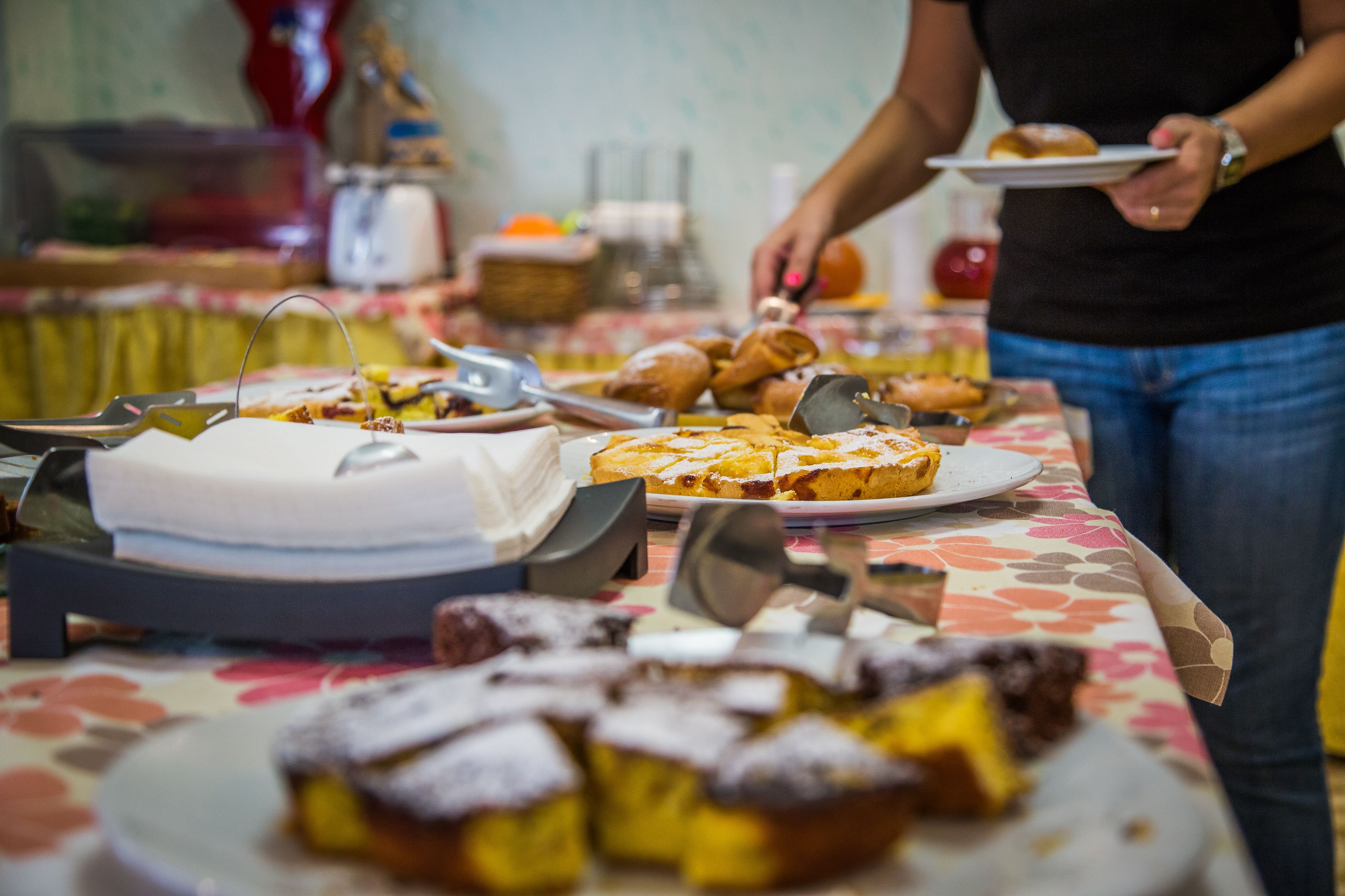 Ein Buffet mit verschiedenen Desserts und einer Person, die Speisen austeilt.