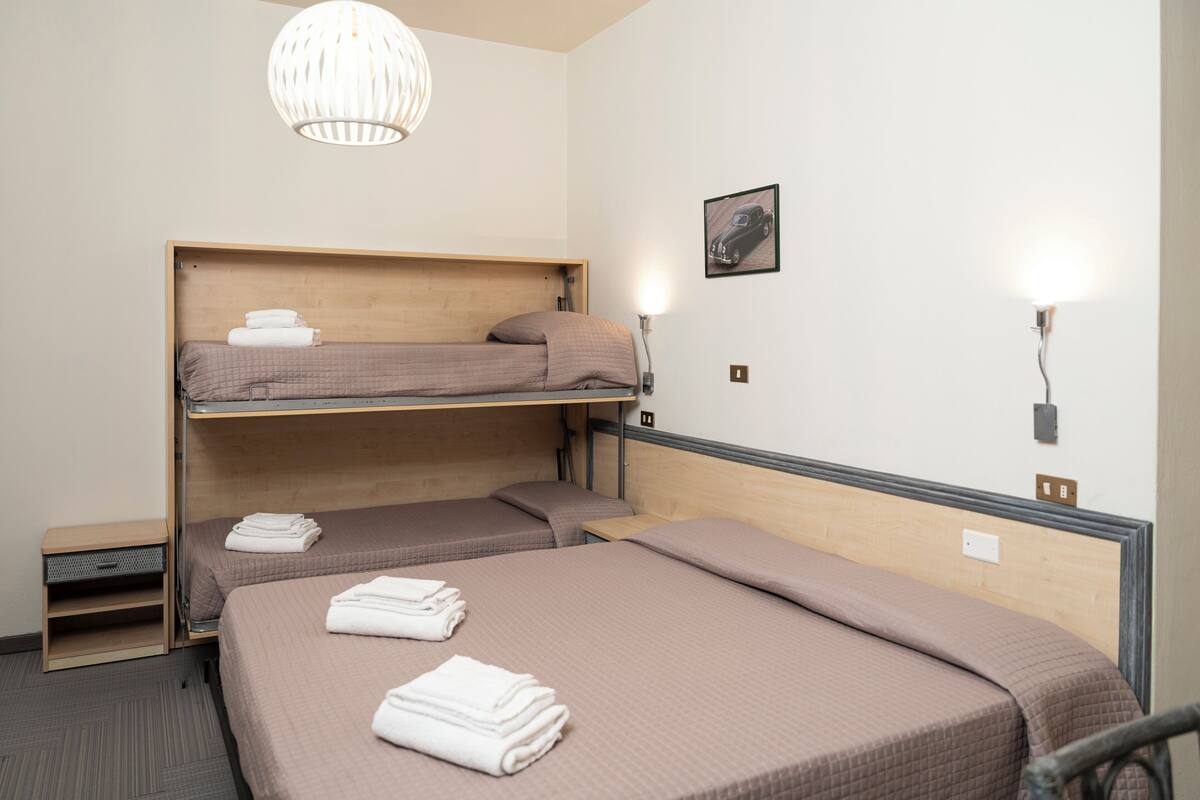 A bunk bed room with a wooden headboard, a wall-mounted light, and a framed picture.