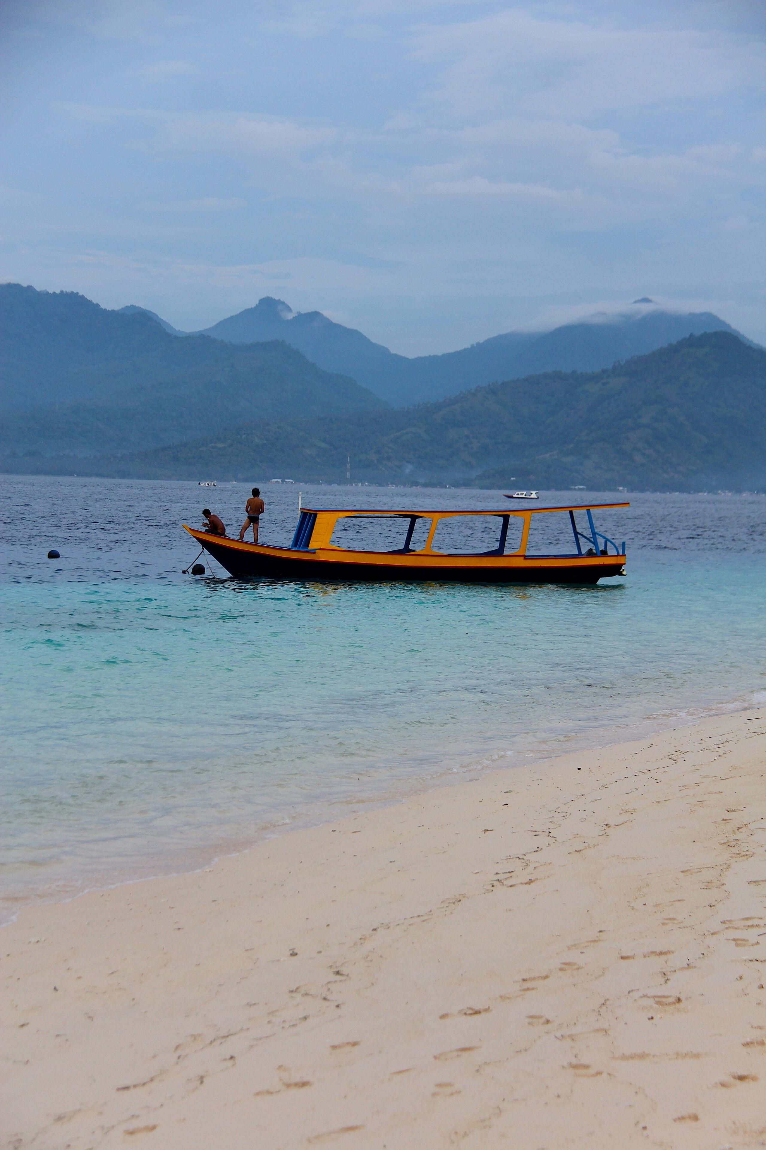 A boat on a beach with mountains in the background.