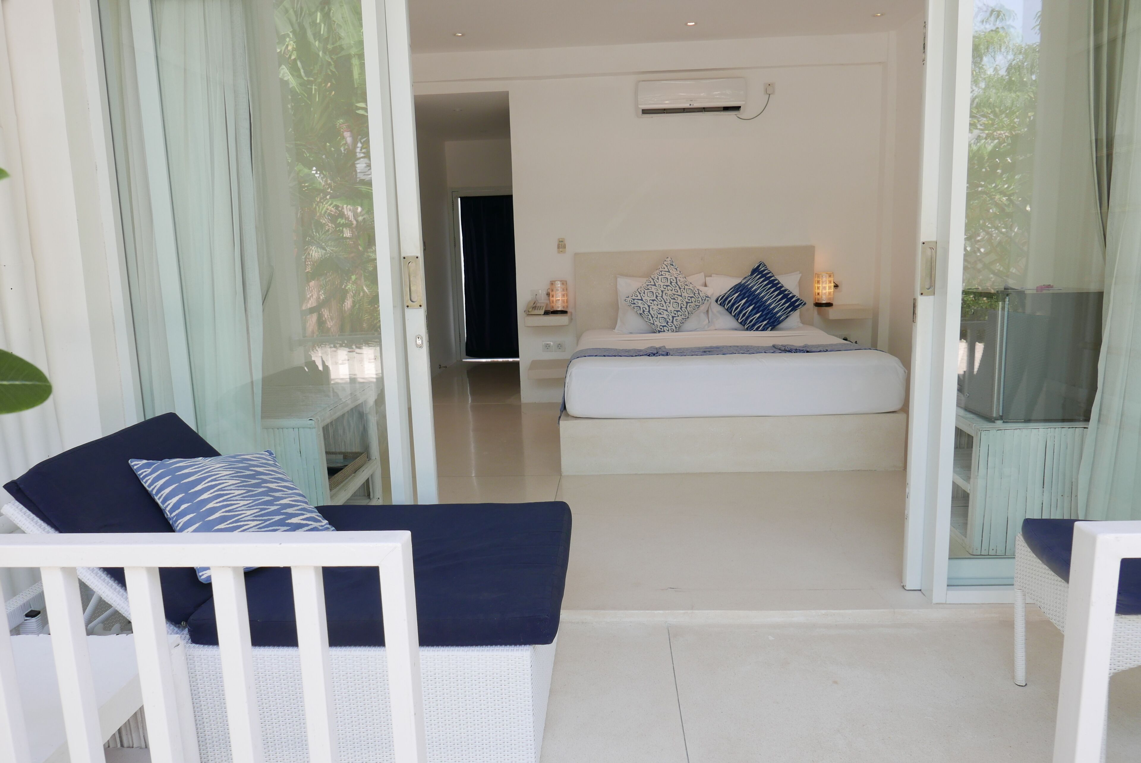 A bedroom with a bed, bedside tables, and a glass door leading to a balcony.