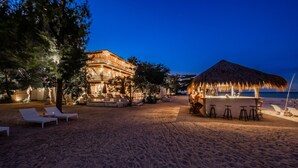 Une propriété située en bord de mer, dotée d’un espace bar, de chaises longues et d’une structure à toit de chaume.