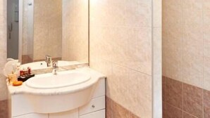 Un baño con tocador blanco, un espejo grande y una bañera.