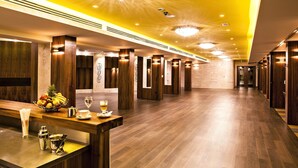 Een hotel lobby met houten vloeren, een receptiebalie met een fruitschaal, een koffiepot en een wijnglas.