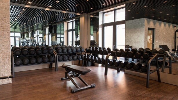 Een fitnessruimte met gewichthefapparatuur, loopbanden en een bank.
