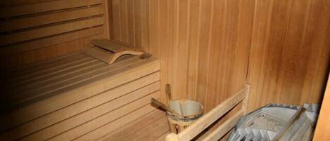 Eine Holzsauna mit Bänken und einem Holzeimer.