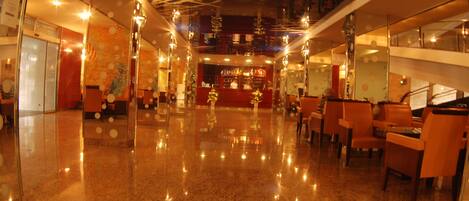 A spacious lobby with a polished marble floor, a reception desk, and seating areas.
