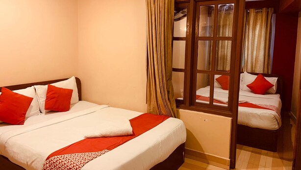 Ein Hotelzimmer mit einem großen Bett, einem kleineren Bett und einem Fenster mit Vorhängen.