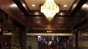 A lobby with a chandelier, potted plants, and a sign thanking patrons. - Mount Royal Hotel (Dubai)