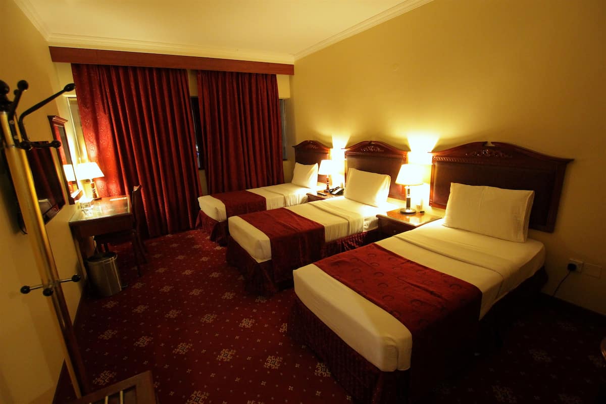 A hotel room with two beds, a desk, and a chair.