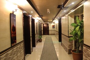 A hotel hallway with a marble floor, a central carpeted walkway, and a potted plant. - Mount Royal Hotel (Dubai)