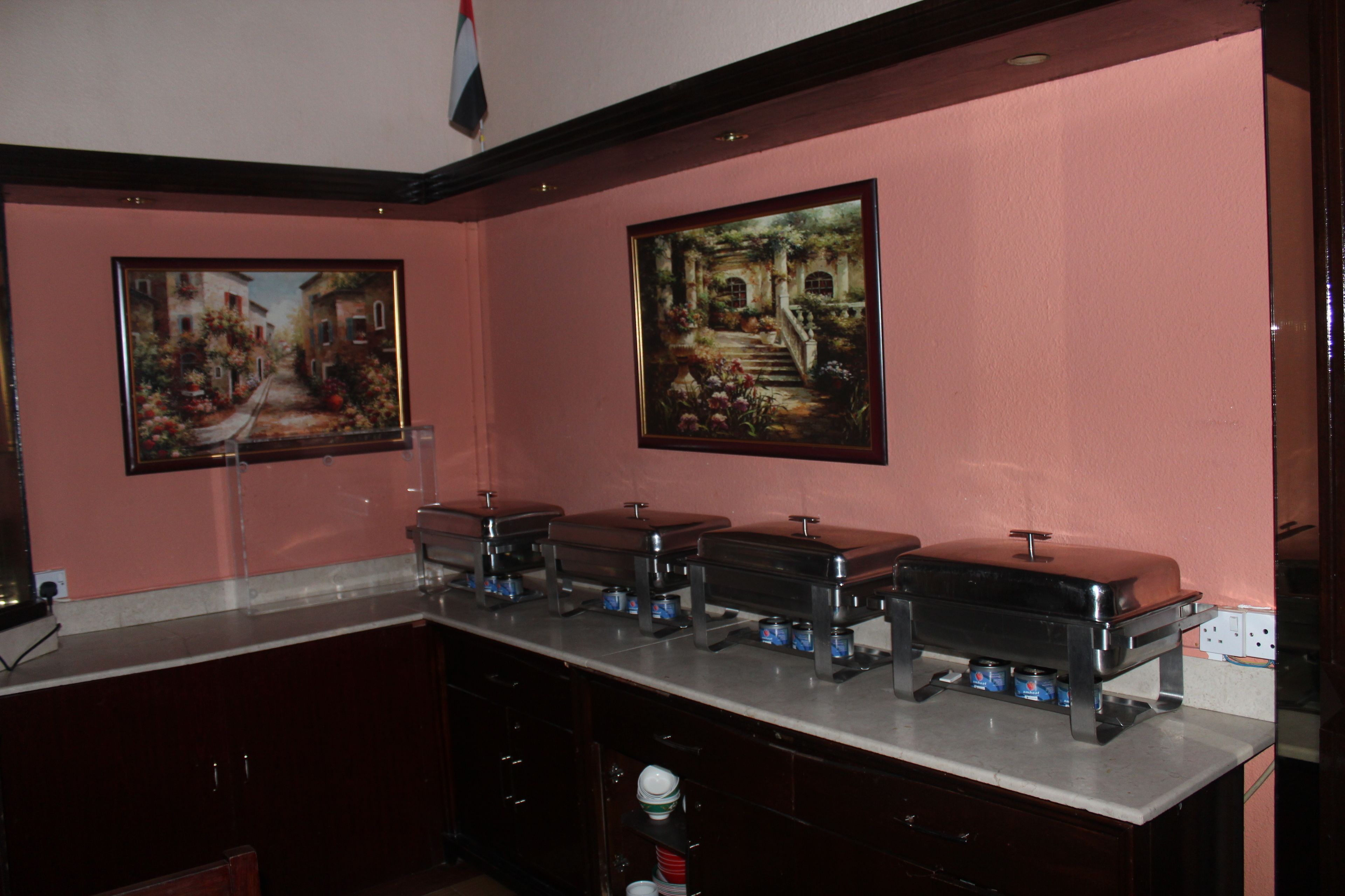 A kitchen with a marble countertop, multiple food dispensers, and two framed paintings on the wall.